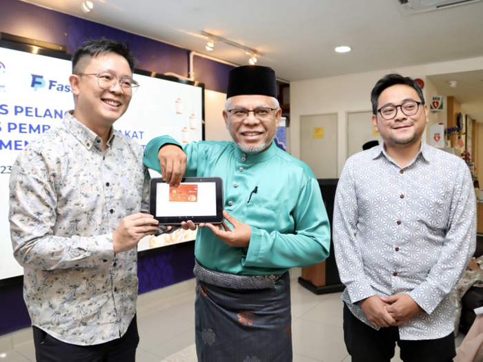 Chief Executive Officer of PPZ-WAIWP Abdul Hakim Amir Osman (middle) demonstrating the Tap on Phone feature.