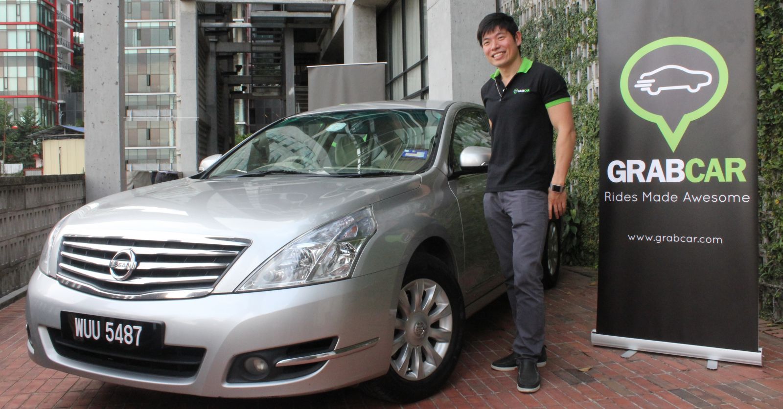 GrabTaxi founder Anthony Tan posing with a GrabCar banner, a new service GrabTaxi launched in 2013.