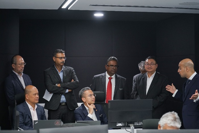 Fahmi Fadzil (seated) listening to a briefing at the Axiata Cyber Fusion Centre. To his right is Axiata chairman, Shahril Ridza. Axiata Group CEO Videk Sood is standing (second from left).