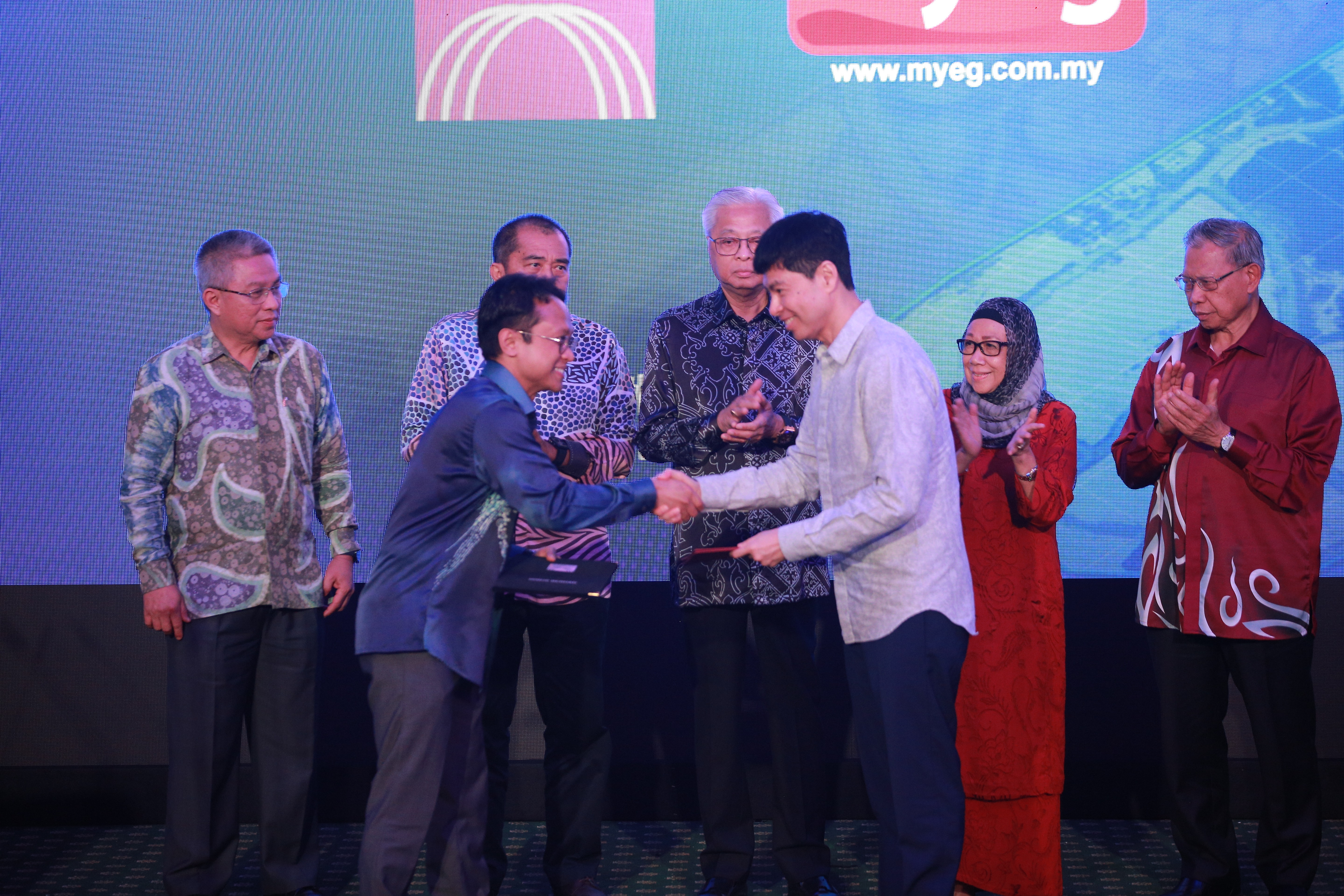 Dr. Iskandar Samad, CEO of MIMOS Global (front, left), and Wong Thean Soon, group managing director of MYEG Services Bhd (front, right) exchanging the MOU under the witness of Ismail Sabri bin Yaakob, Prime Minister of Malaysia